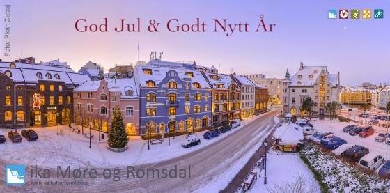 Julekort med god jul og godt nytt år på på eit bilde av ei opplyst bygate i Ålesund i vinterskrud, tatt frå høgt hald.