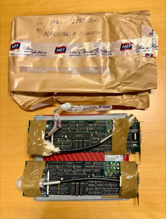 En pakke i brunpapir og tape merka MRF, ved sidan av to eldre datamaskinkort.