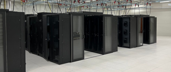 Stort rom med flere rekker svarte dataracker med kobling til taket.