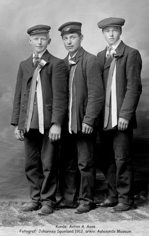 3 unge karar pent oppdressa med skyggelue og lange 17. maisløyfer står side om side i studio og ser mot fotografen