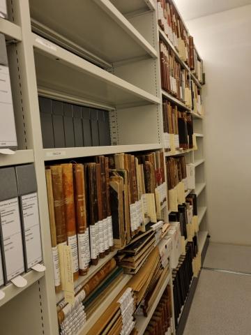 Bilde inn i ein arkivreol av mange gamle protokollar i hyller
