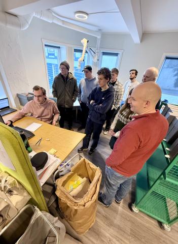 studentar står ved ein arbeidspult og får forklart ordning av arkiv